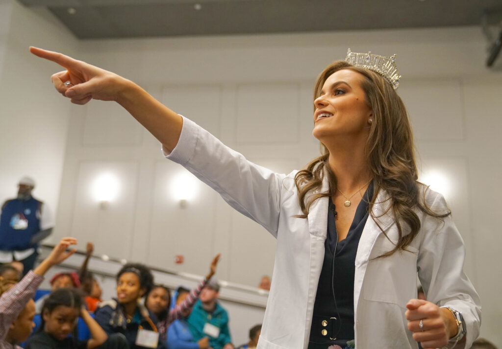 Miss America speaking at a public event with young children.